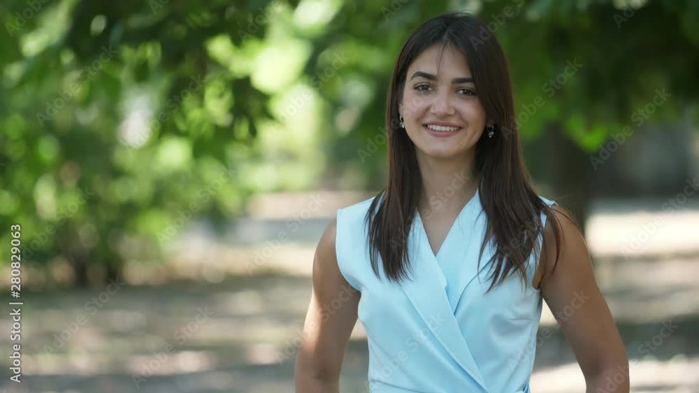 Lovely girl with sparkling eyes turning back and forth laughing in park in summer Lovely girl with sparkling eyes turning back and forth laughing in park in summer