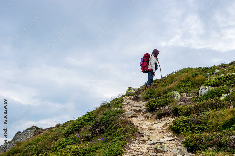 Young girl with red backpack trekking in high mountain route.
