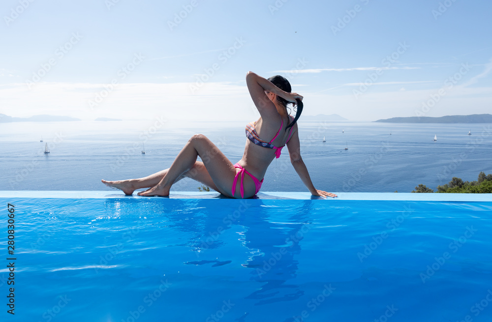 Beautiful woman is relaxing on an infinity pool