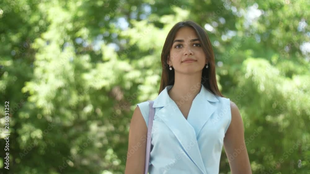 Beautiful girl standing and smartening up in green alley on a sunny day in slo-mo Beautiful girl standing and smartening up in green alley on a sunny day in slo-mo