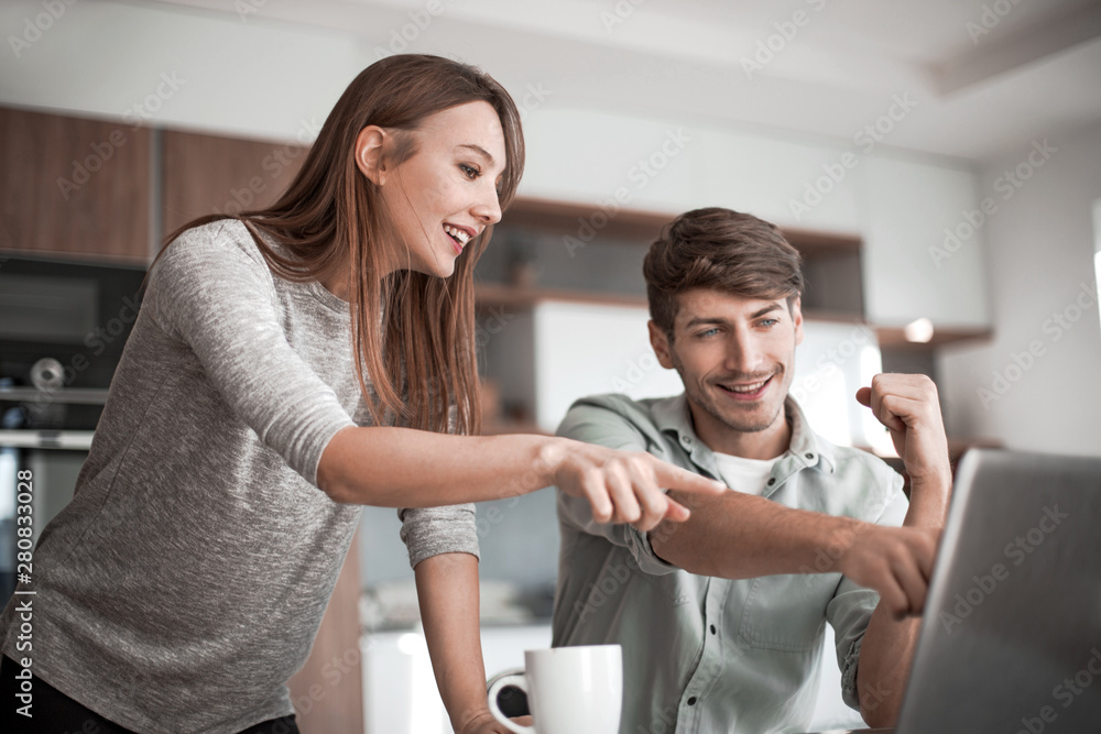 Young couple looking discussing online news in the kitchen Young couple looking discussing online news in the kitchen