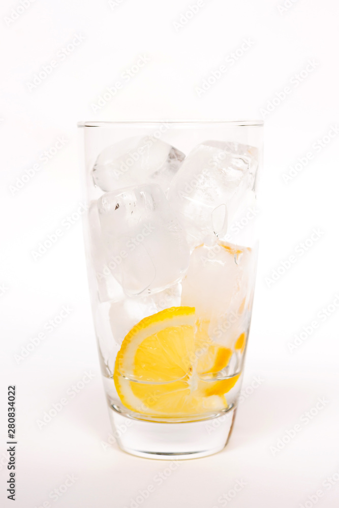 Glass of ice with lemon slice isolated on white background; prepare for popular morning healthy beverage Glass of ice with lemon slice isolated on white background; prepare for popular morning healthy beverage