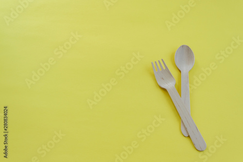 Bamboo wooden spoons and forks on yellow background with space for text. Eco friendly kitchen utensils. Ecological concept.