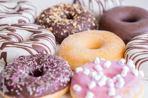 Close up of different donuts with  sugar, chocolate frosted, pink glazed and sprinkles