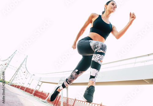Running young woman in sport clothes outdoors