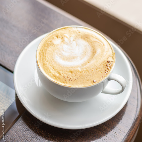 White Cup of Cappuccino with latte art on wooden table