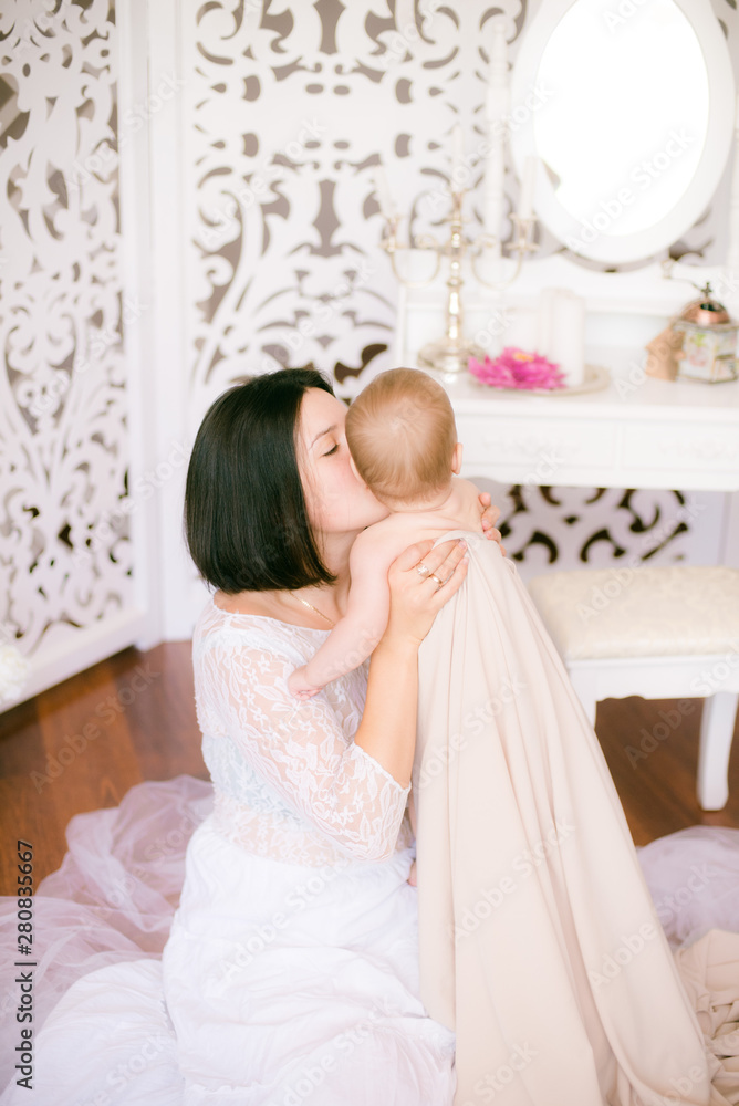 Young mom with a baby in her arms in the bright boudoir bedroom Young mom with a baby in her arms in the bright boudoir bedroom