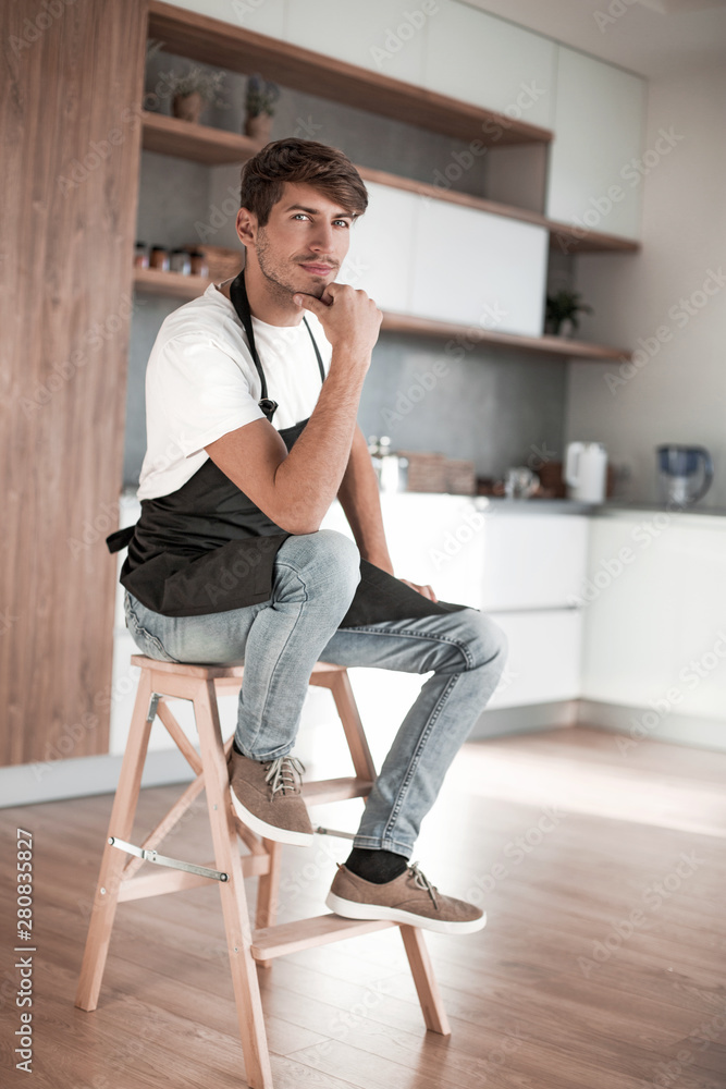 attractive man with an apple sitting in a home kitchen