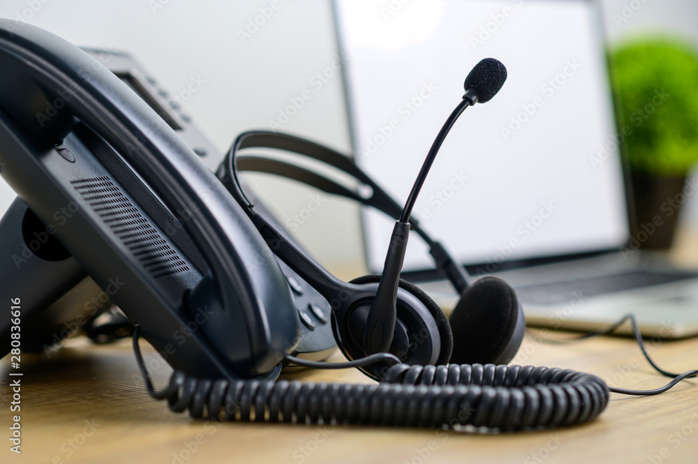 Close up IP telephone with head set on wood table and blurred of laptop computer on background Close up IP telephone with head set on wood table and blurred of laptop computer on background