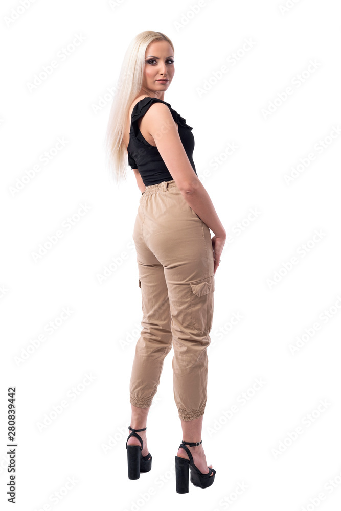 Back view of serious confident blonde woman with attitude in stylish clothes turning and looking at camera. Full body isolated on white background. Back view of serious confident blonde woman with attitude in stylish clothes turning and looking at camera. Full body isolated on white background.