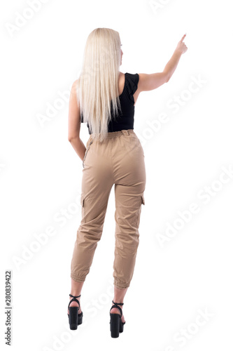 Back view of straight hair stylish blonde woman pointing finger up using touch screen. Full body isolated on white background. 
