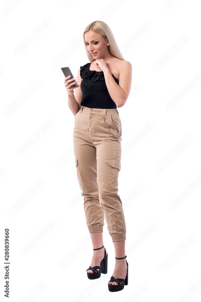 Confused uncertain young blonde woman reading and using smart phone social media. Full body isolated on white background. Confused uncertain young blonde woman reading and using smart phone social media. Full body isolated on white background.