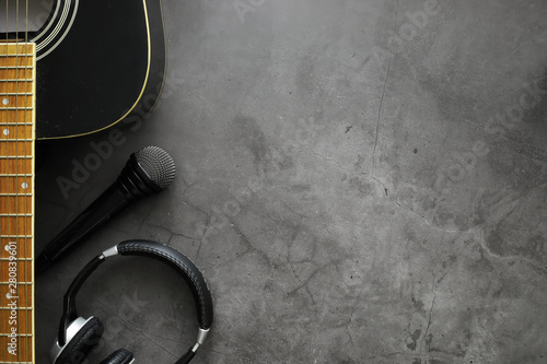 Guitar and accessories on a stone background. Desk musician, headphones, microphone. photo