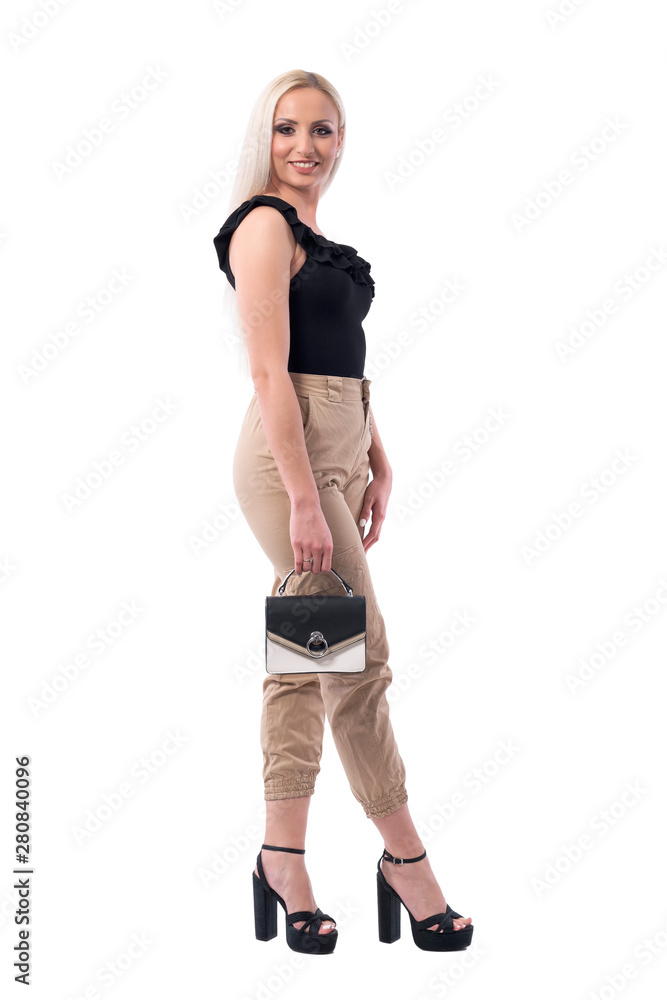 Side view of happy fashionable stylish blonde woman holding elegant purse. Full body isolated on white background. Side view of happy fashionable stylish blonde woman holding elegant purse. Full body isolated on white background.