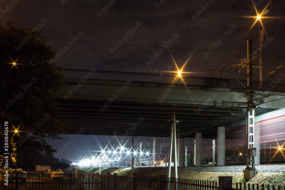 Novogireevo railway station in Moscow Russia with a train passing under the road bridge at night