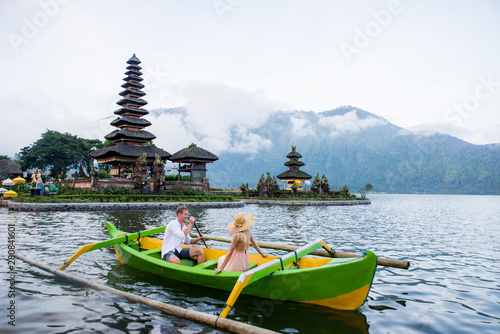 Young couple paddling on a wooden boat at Pura Ulun Danu Bratan photo