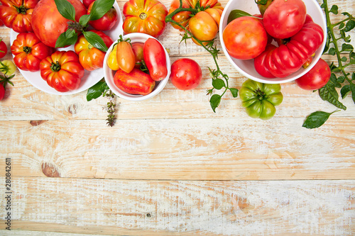 Mix of tomatoes background. Beautiful juicy organic red tomatoes on white wooden table background. Clean eating concept. Copy space  flat lay..