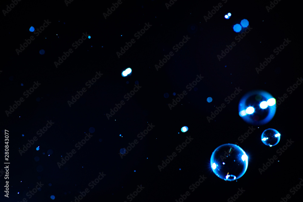 Naklejka premium Soap bubbles of blue color on a dark background