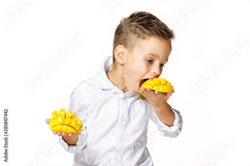 handsome boy in a white shirt is eating a mango