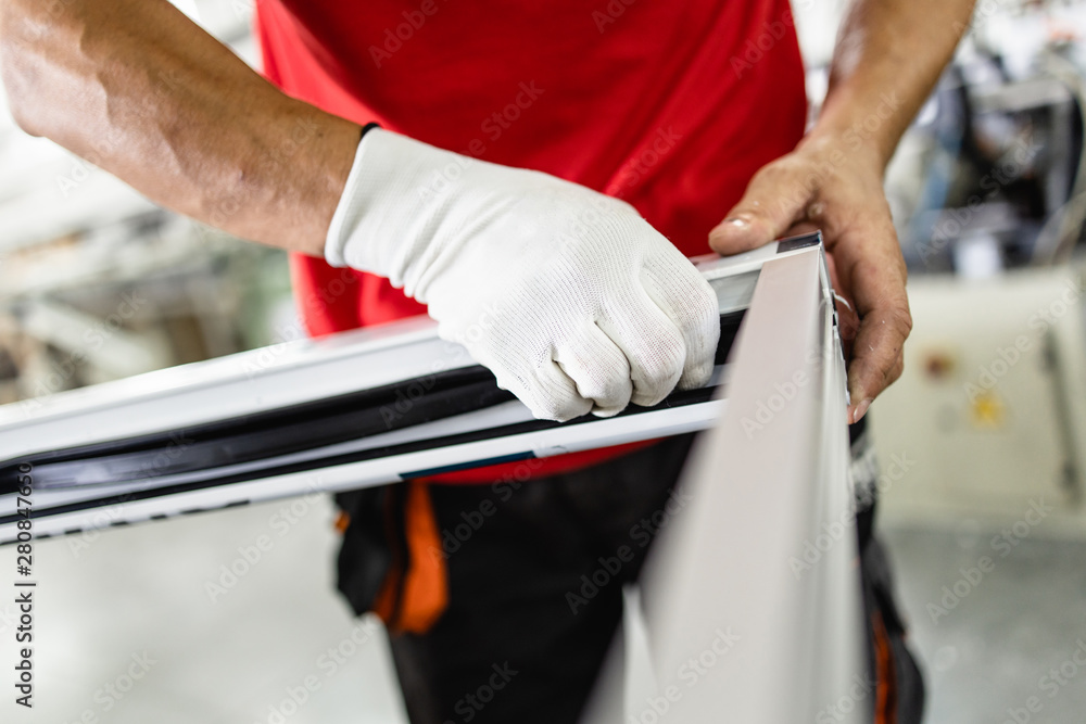 Obraz premium Manual worker assembling PVC doors and windows. Manufacturing jobs. Selective focus. Factory for aluminum and PVC windows and doors production.