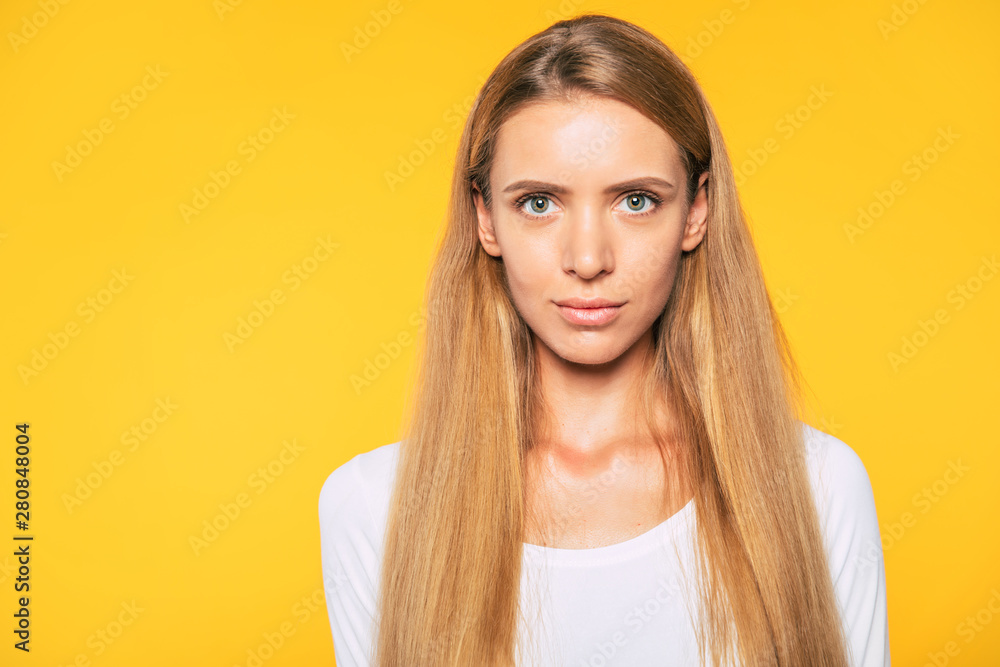 Beautiful blonde young woman in casual white wear is posing over colorful wall. Beauty and fashion concept. Blonde student girl. Beautiful blonde young woman in casual white wear is posing over colorful wall. Beauty and fashion concept. Blonde student girl.