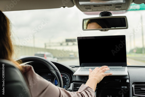 Business woman working using laptop while driving car on the highway . space for text