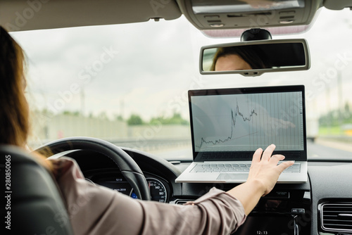 Business woman working using laptop while driving  car  on the high speed on the highway .