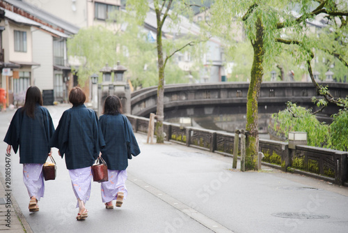 Japanese woman family wearing kimono and walking at Kinosaki Onsen village street in Toyooka City, Hyogo, Japan. See from back side in morning. Japan traveler trip.