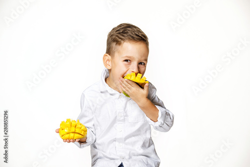 handsome boy in a white shirt is eating a mango