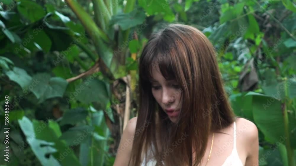 Beautiful girl model in white dress posing on a background of tropical plants. Beautiful girl model in white dress posing on a background of tropical plants.
