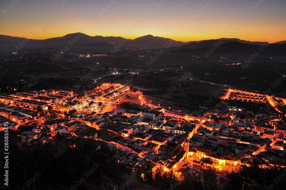Cártama town in Málaga Province seen by night with the sun setting behind the mountains. Andalusia, Spain