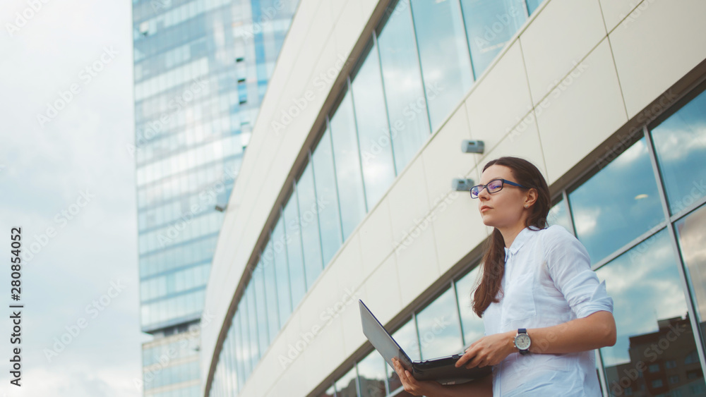 Young ambitious woman with a laptop in her hands on the background of the business center.