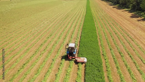Aerial view of tractor in the field in summer. Special technology for mowing green grass in process on the field background in sunny day.