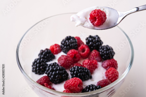 Ice cream with raspberry, blackberry berries with spoon in glass bowl on white background