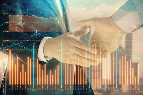 Double exposure of financial graph on cityscape background with two businessman handshake. Concept of stock market deal © Andrey