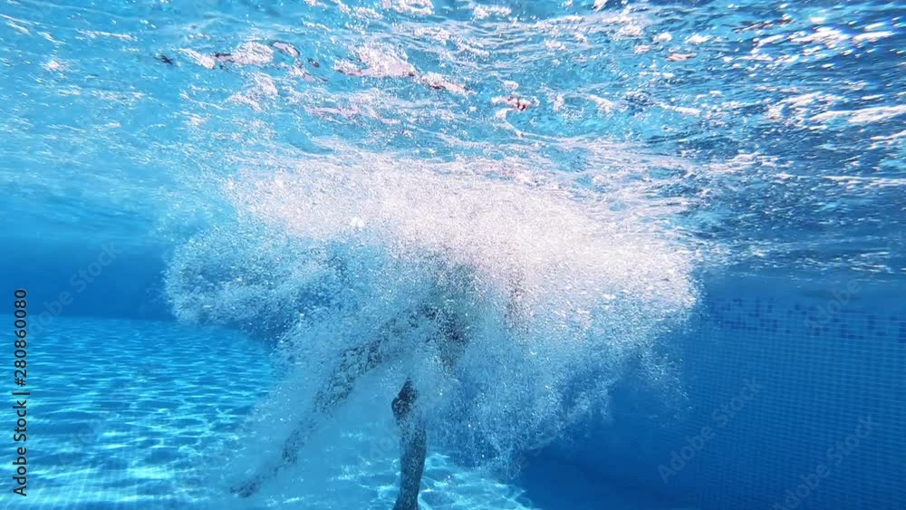 Boy jump into the blue clear water making many bubbles. Young boy