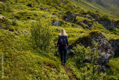 Woman goes on tourist hiking trail along ocean and mountains in Norway. Active recreation, healthy lifestyle. Enjoys scenic view. Beautiful nature. Travel, adventure. Sense of freedom. Explore North