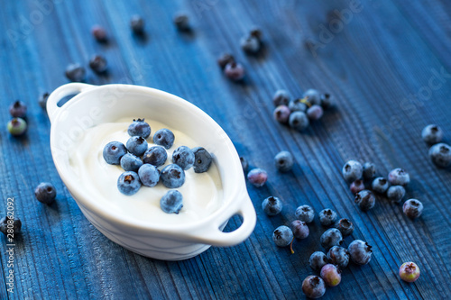 fresh tasty blueberry with natural yoghurt on wooden background