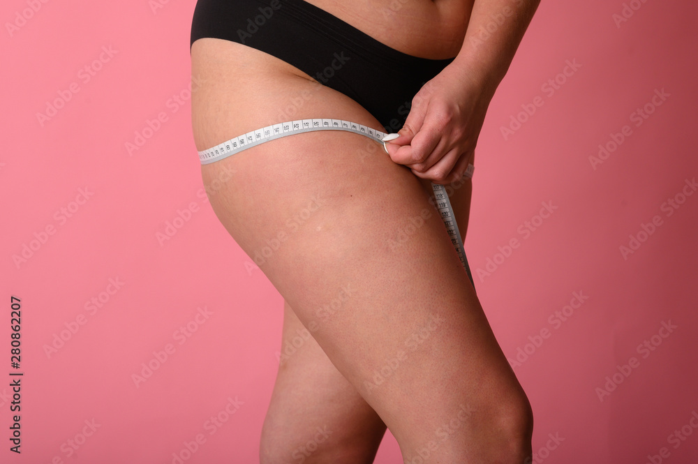© kalinichenkod - Body positive girl measures thigh volume. size plus. girl with measuring tape