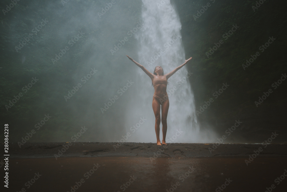 Beautiful girl having fun at the waterfalls in Bali. Concept about wanderlust traveling and wilderness culture