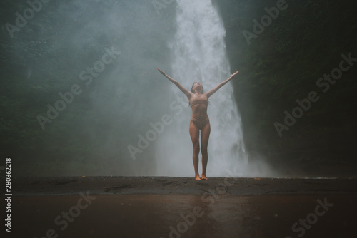 Beautiful girl having fun at the waterfalls in Bali. Concept about wanderlust traveling and wilderness culture