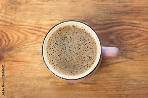 A cup of coffee on wooden background. Beautiful foam  pink ceramic mug  stylish toning  copy space.