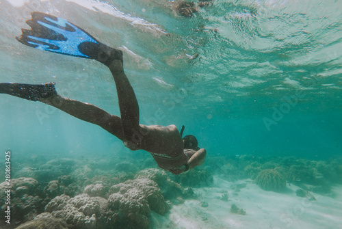 Beautiful woman swimming underwater in a tropical sea full of corals. under water shot with action camera. concept about wanderlust travels © oneinchpunch