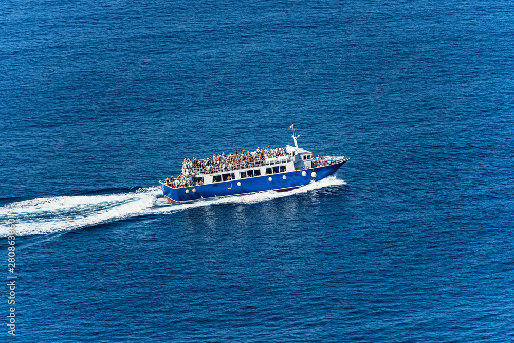 Blue ferry boat with many tourists during sailing to the Cinque Terre in the Mediterranean Sea. Gulf of La Spezia, Liguria, Italy, Europe