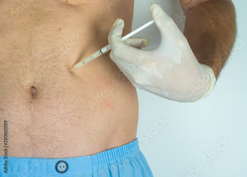 man with surgery pants, siringe in a hand with glove taking off the fat, white background
