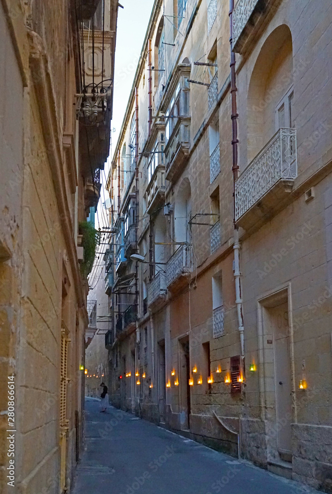 Narrow street in old town, stone houses, balconies. lanterns with candles, Birgu Festival candlelight Festival, Malta 