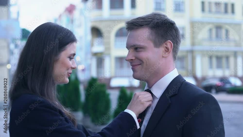 Wife of politician straightening husbands tie, hiding with hands from camera Wife of politician straightening husbands tie, hiding with hands from camera