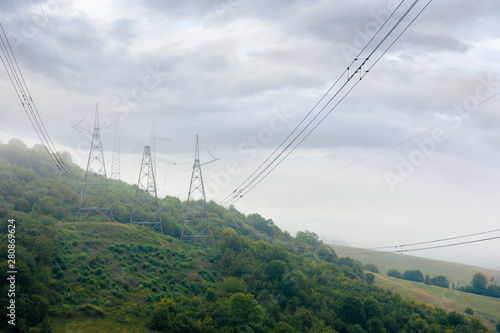 high voltage power lines tower in mountains. energy delivery background. efficient electricity delivery concept. hazy weather with overcast sky