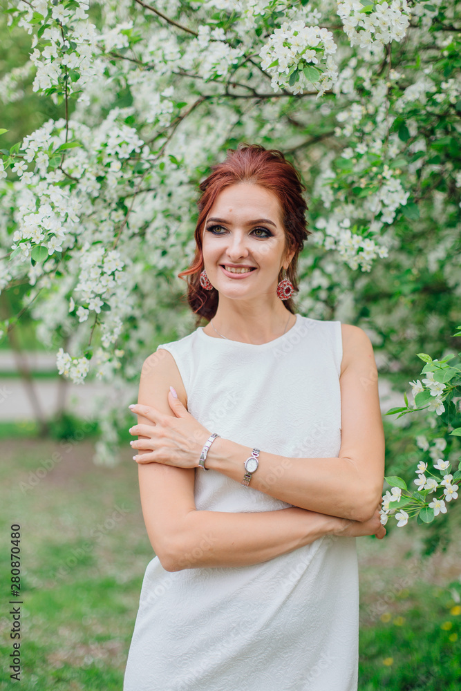 Charming woman wearing beautiful white dress under the apple tree Charming woman wearing beautiful white dress under the apple tree