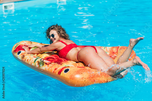 Close up photo. Sexual woman ass lying on float pizza in pool. Happy time, summer vacation.